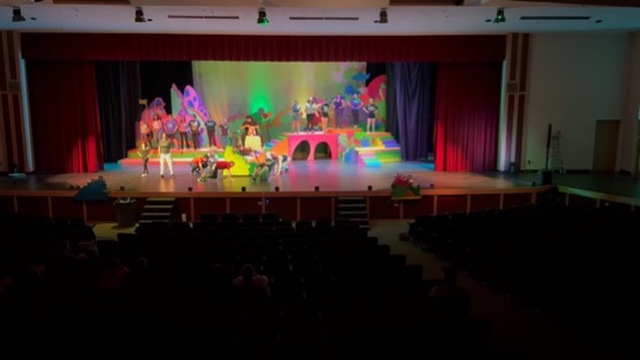 A Rexburg Community Theatre production under colorful stage lighting.