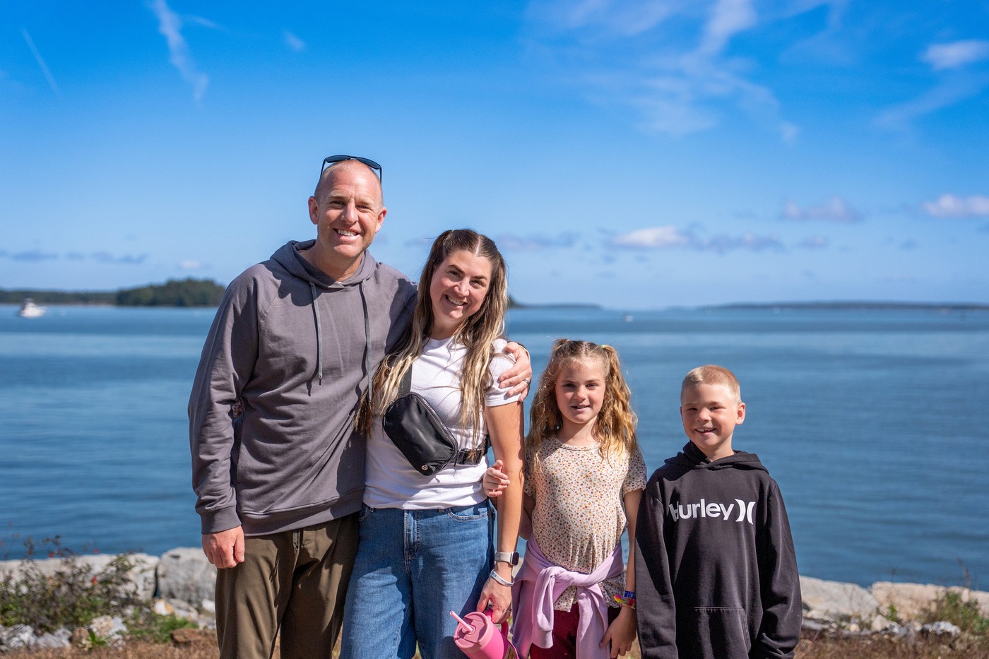 The Robinson family smiling together beside the water.