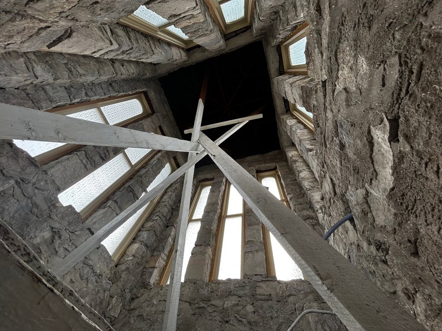Looking upward inside a stone Tabernacle tower at wooden cross-bracing and narrow windows.