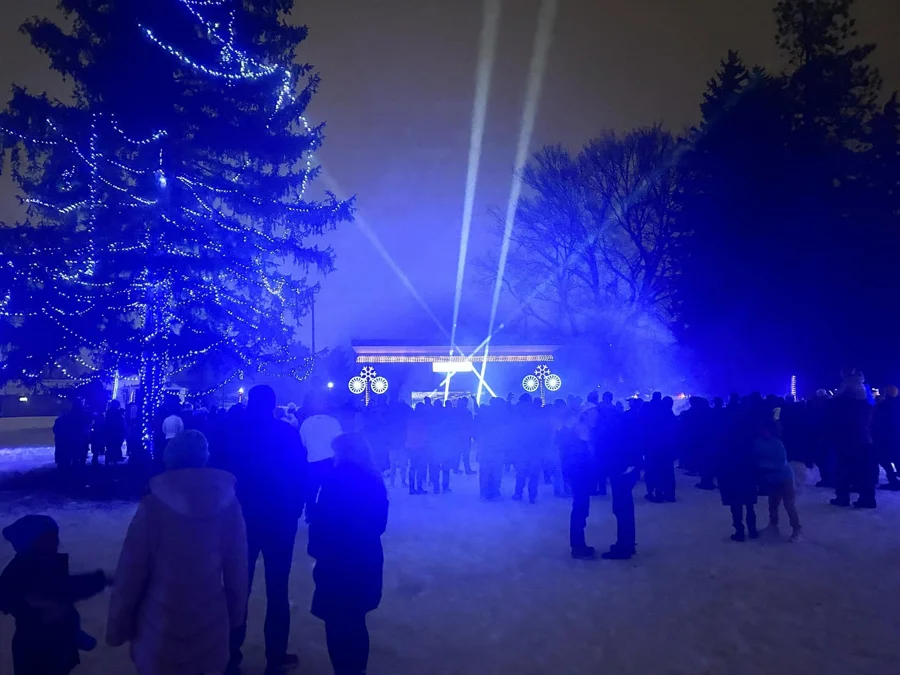 Guests gather in the snow as blue light and skyward beams illuminate Luminosity at Porter Park during the 2024 season.