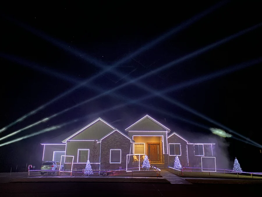 The first-year Robinson Family Light Show outlines the family home beneath crossing sky beams in Rexburg, Idaho.
