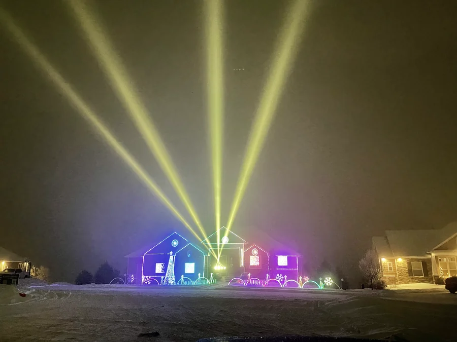 The 2022 Robinson Family Light Show fills the family home with rainbow color beneath gold sky beams on a snowy Christmas Eve in Rexburg, Idaho.