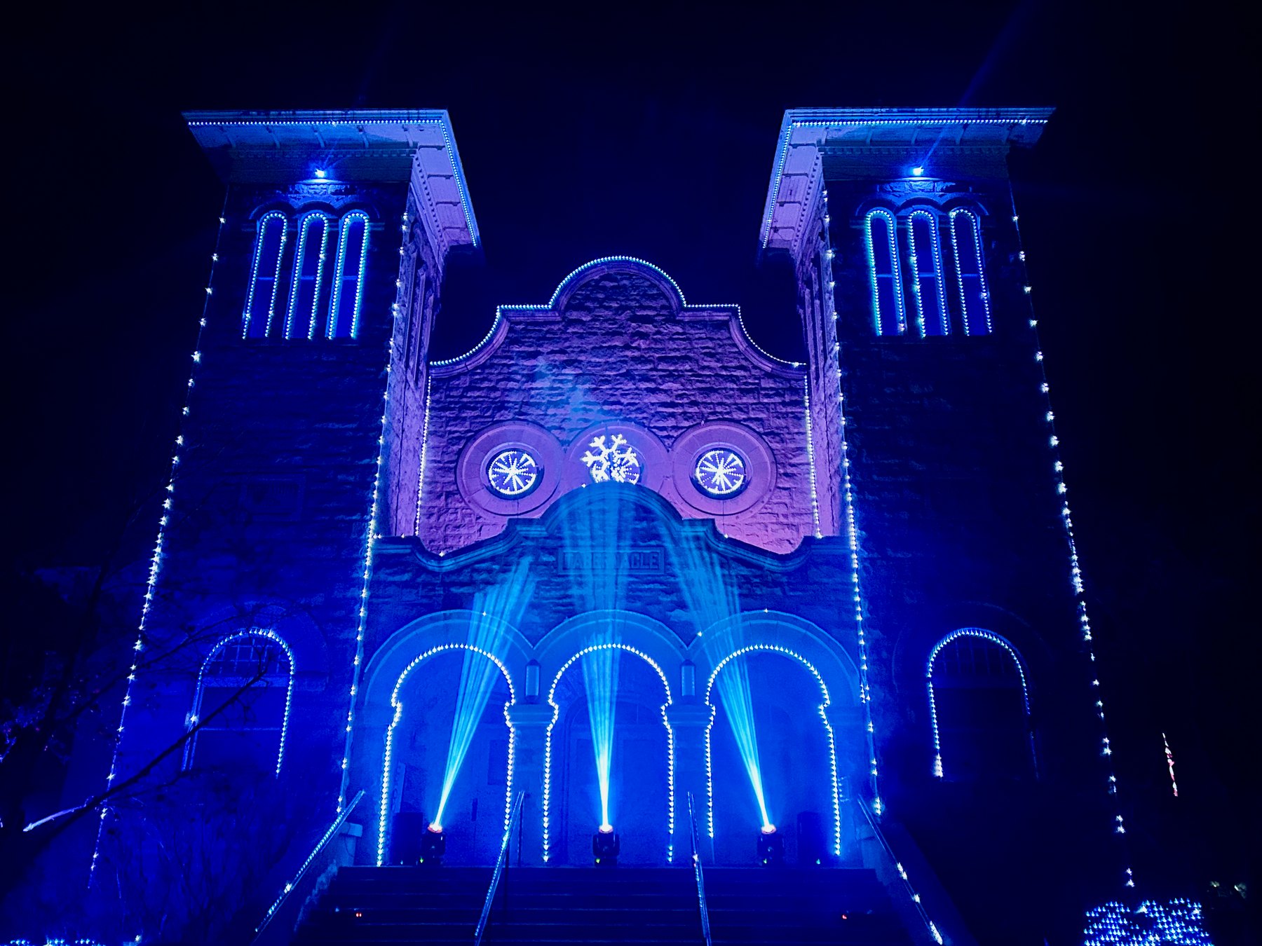 The Rexburg Tabernacle glowing deep blue with beams rising from the steps